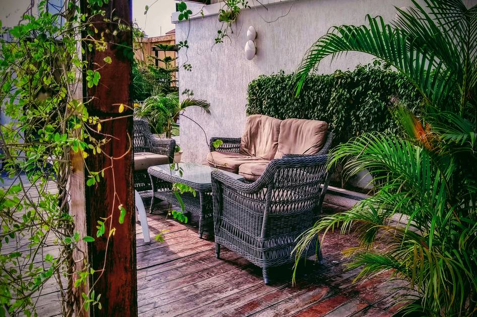 Close-up of a weather-resistant wicker garden chair with floral cushions beside a rustic side table