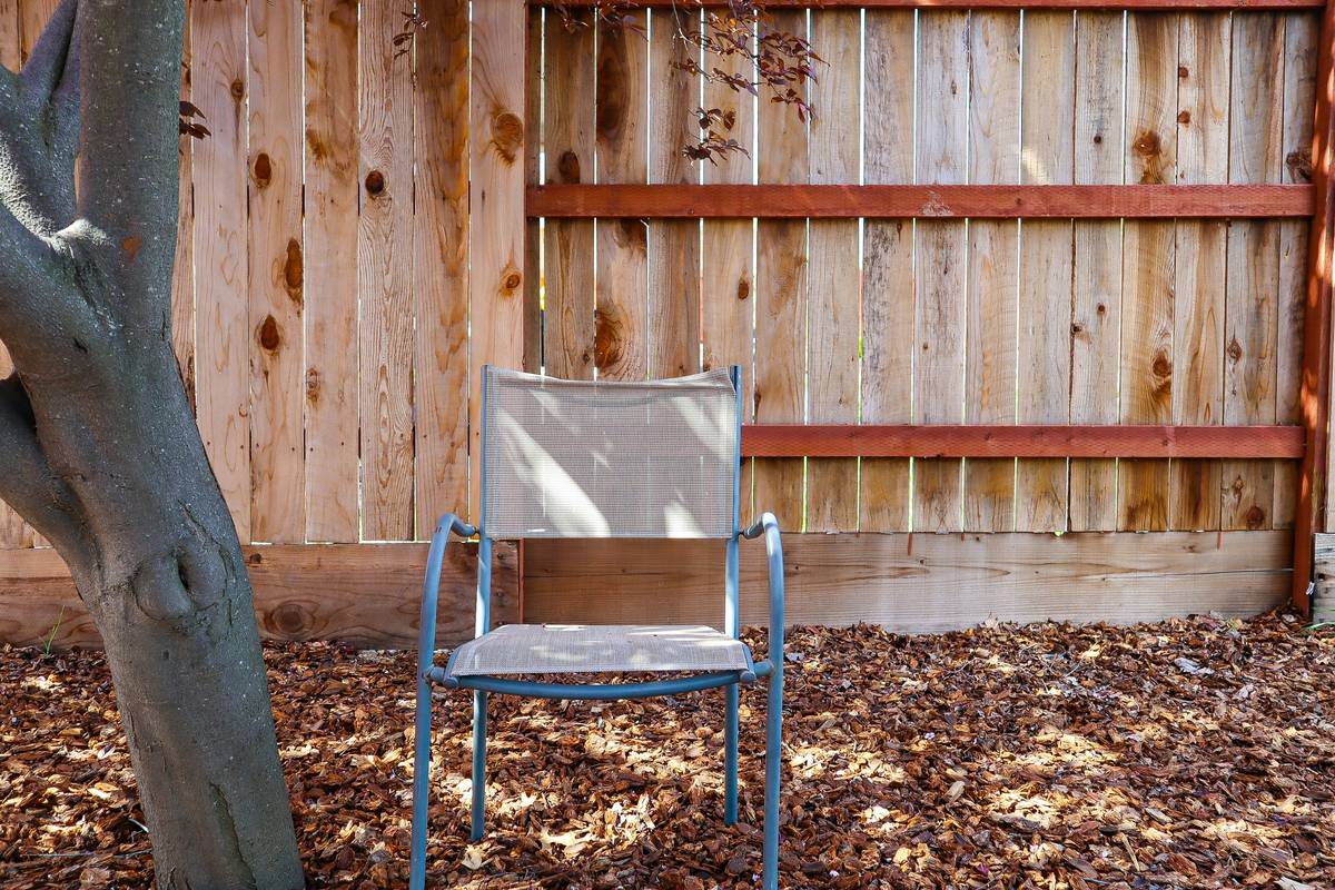outdoor furniture wooden chairs arranged around a patio table with potted plants and string lights